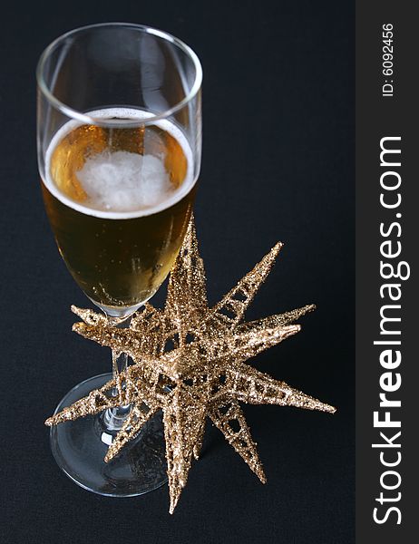 A golden christmas star with a glass of sparkling wine. A golden christmas star with a glass of sparkling wine