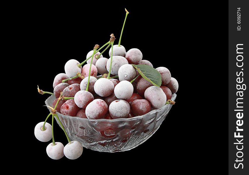 The frozen berries of a cherry in a glass vase on a black background.