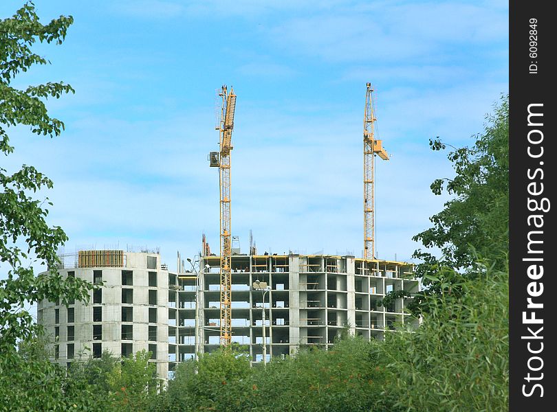 Construction of a new multi-storey house with the help of elevating cranes.