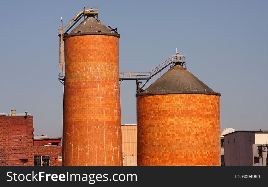 Two brick silos from a pulp mill with blue sky background.
