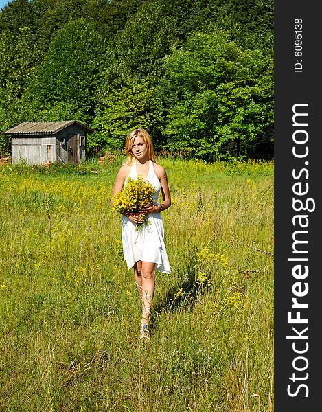 Blond woman in white dress walking through the meadow. Blond woman in white dress walking through the meadow