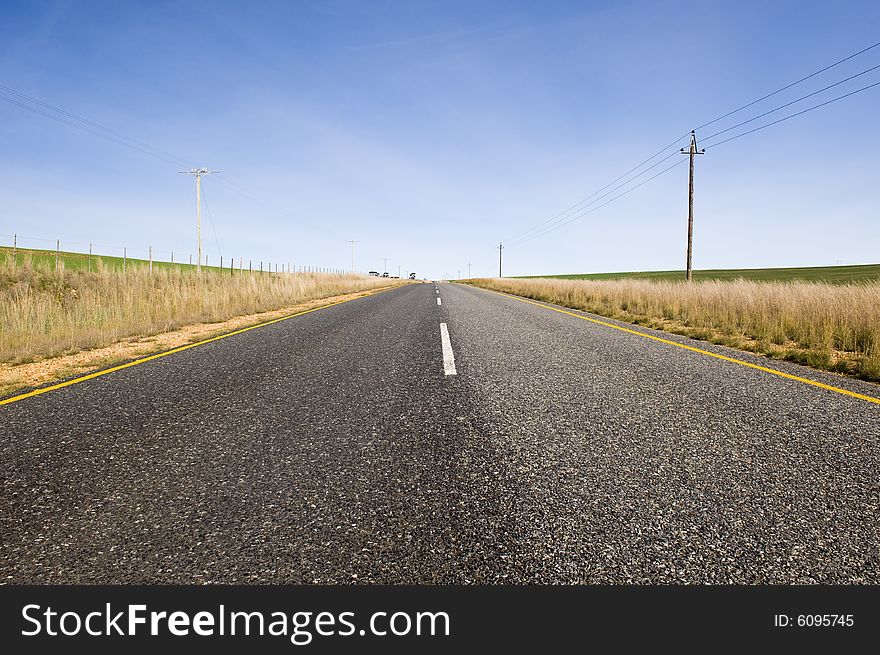 A deserted country road running through some green fields. A deserted country road running through some green fields.