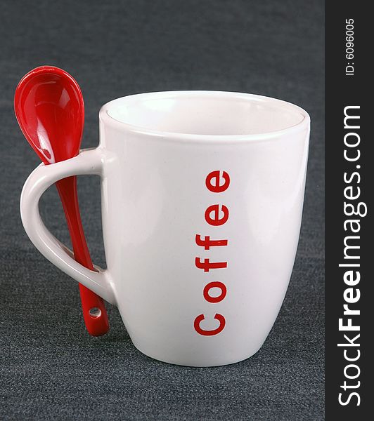 A coffee mug and a red spoon.