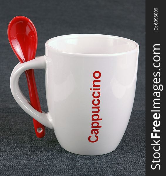 A cappuccino mug and a red spoon. A cappuccino mug and a red spoon.