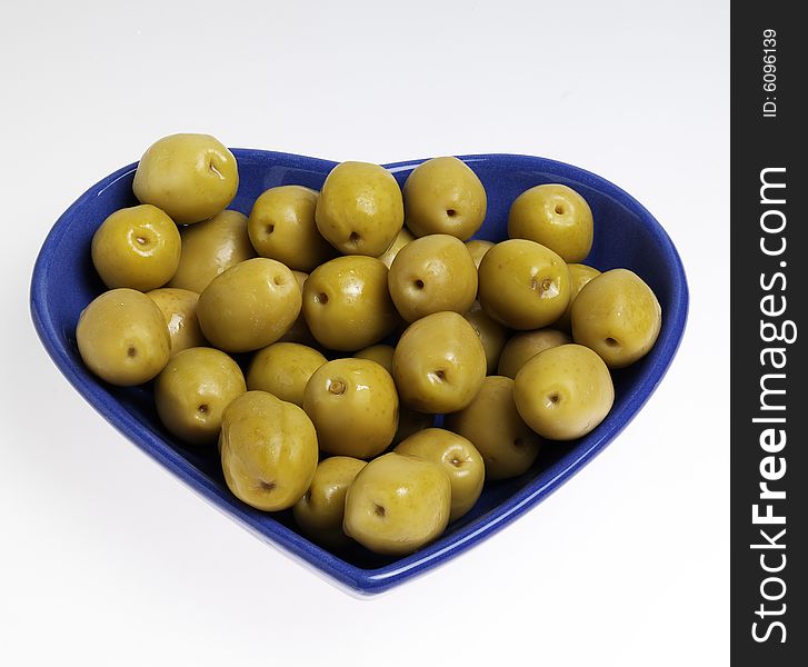 Green olive with hearth shape's cup on the white background.