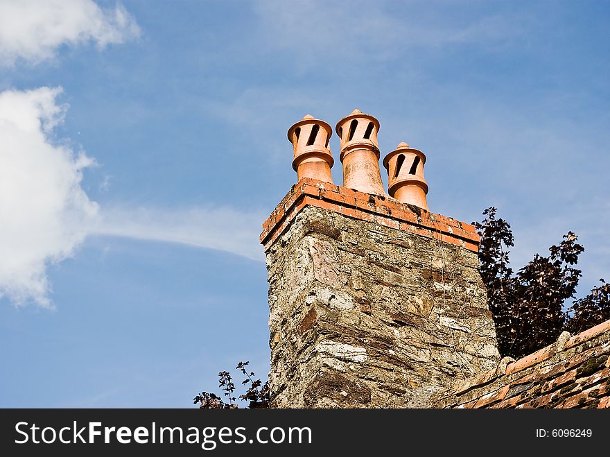 A trio of classic French chimney pots against a summer sky