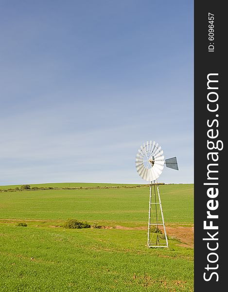 A traditional windmill turning in the wind and pumping water out of the ground into a catchment dam. A traditional windmill turning in the wind and pumping water out of the ground into a catchment dam.