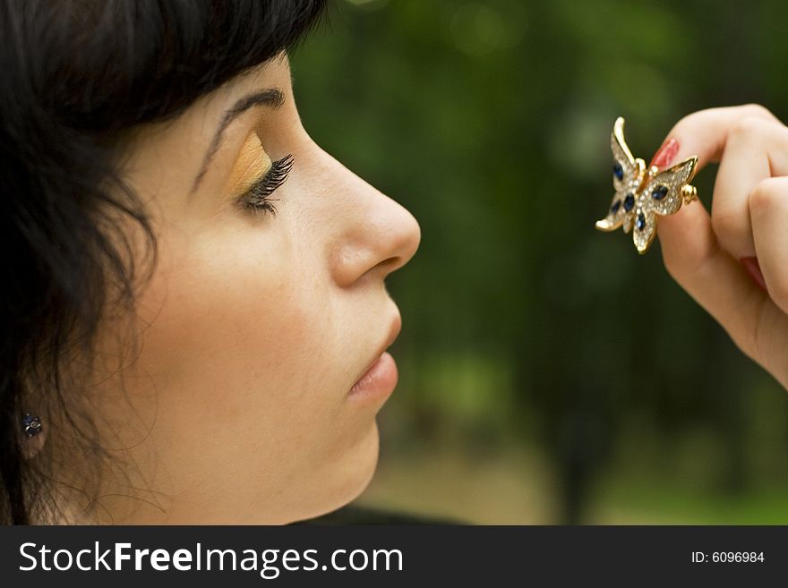 Outdoor portrait of pretty young brunette with brooch-butterfly