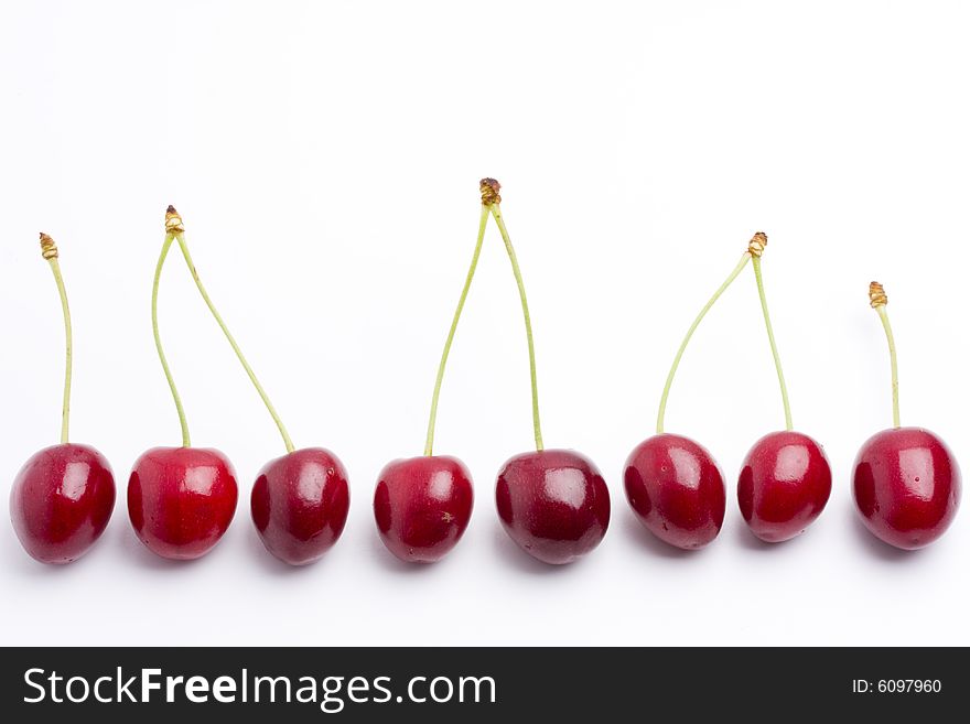 Row of red cherries on white background