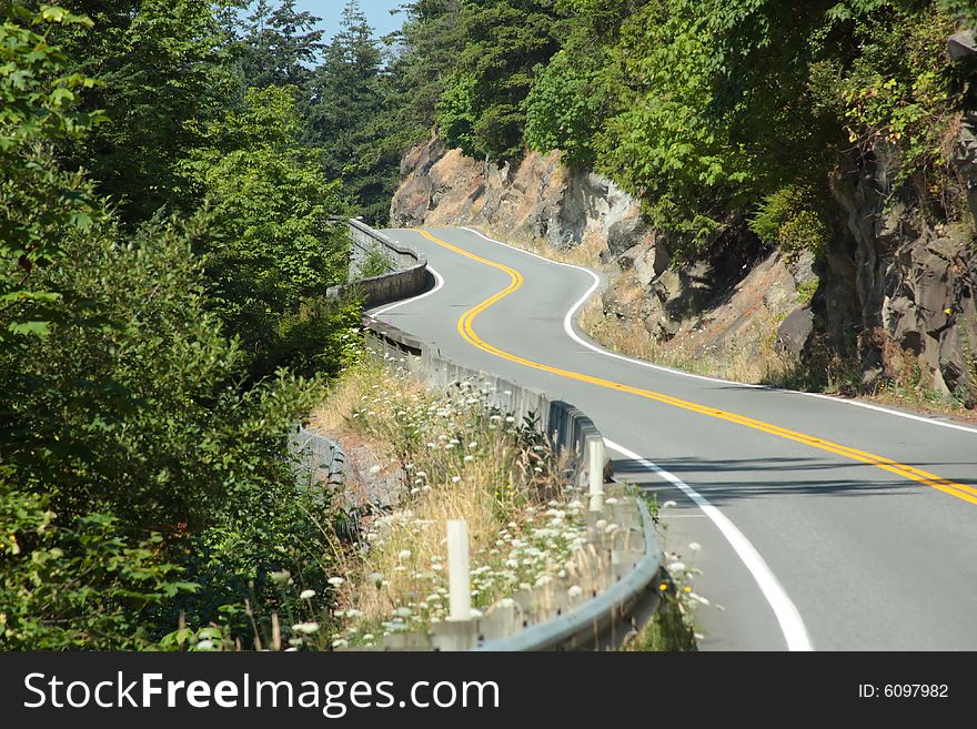 Winding road along a hillside through the forest. Winding road along a hillside through the forest.