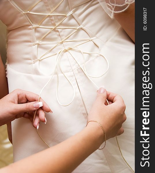 Young woman tightening the courset of a bride. Young woman tightening the courset of a bride