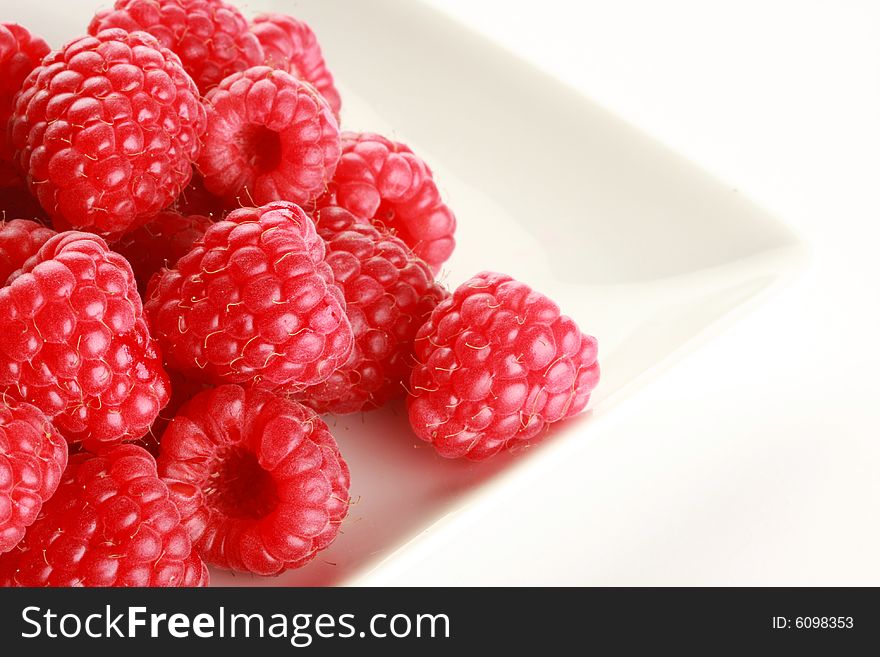 Raspberries on white dish, shot in studio isolated on white. Raspberries on white dish, shot in studio isolated on white