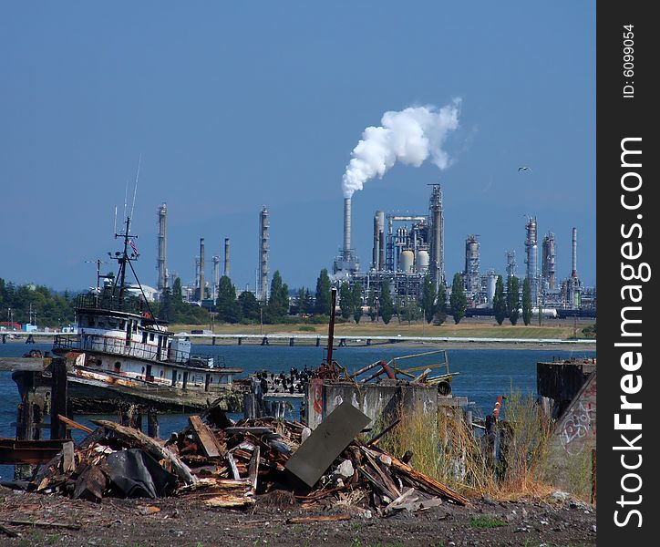 View of an oil refinery from a junked dock area, with trash and vandalism in the foreground. View of an oil refinery from a junked dock area, with trash and vandalism in the foreground.