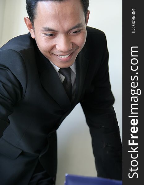 Asian business man looking to laptop in office smiling