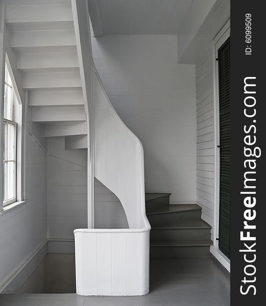 White wooden spiral stairs winds from one floor to another through the back porch. White wooden spiral stairs winds from one floor to another through the back porch.