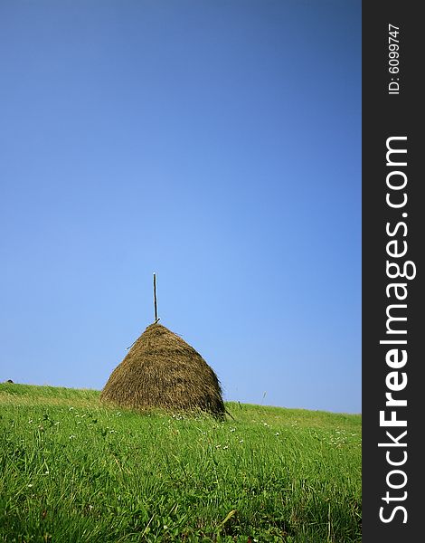 Haystack on a background of the blue sky and green grass