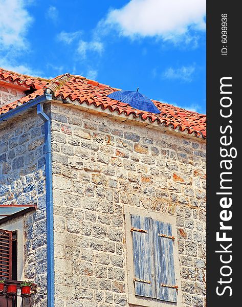 Old stone house exterior in Montenegro - Budva, umbrella on roof. Old stone house exterior in Montenegro - Budva, umbrella on roof