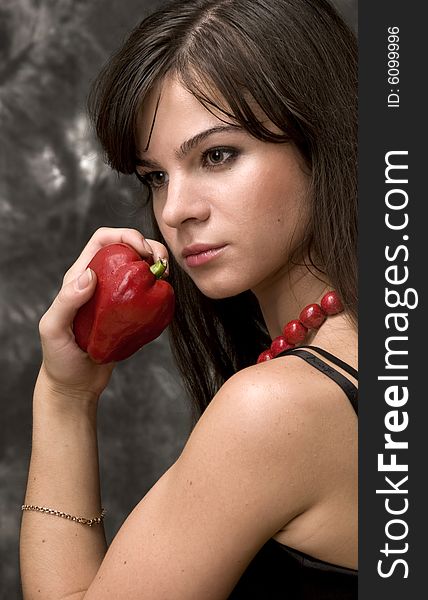 A beautiful young girl holds a sweet cayenne in a hand. A beautiful young girl holds a sweet cayenne in a hand