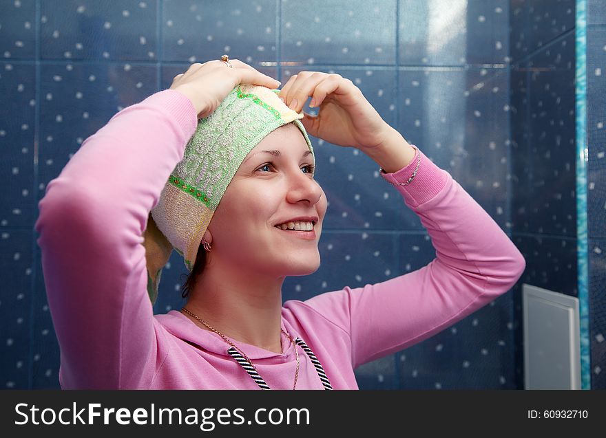 Young brunette smiling woman in a bathroom with a towel on her head