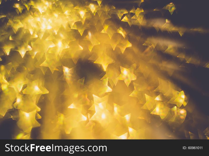 Festive background with defocused golden glitters, bokeh in a shape of a star. Festive background with defocused golden glitters, bokeh in a shape of a star.