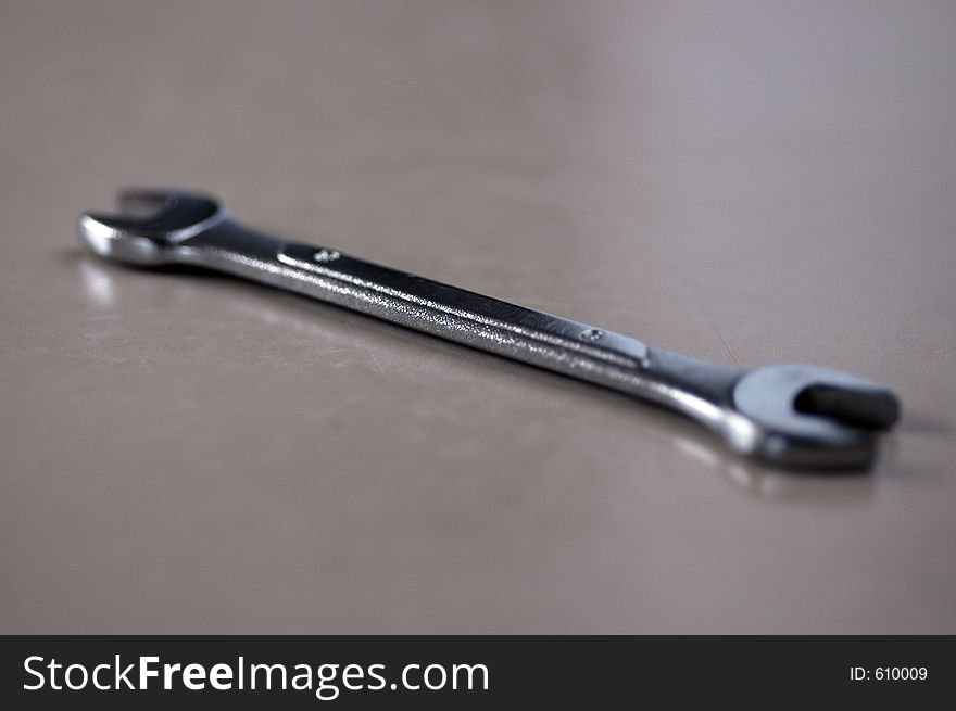 A shiny alloy open-ended auto wrench in shall DOF on a smooth surface