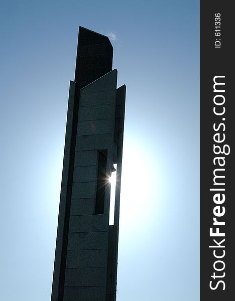 Image of a bell tower with the sun behind it, causing a sunburst effect as it shines through a gap in the building. Image of a bell tower with the sun behind it, causing a sunburst effect as it shines through a gap in the building.