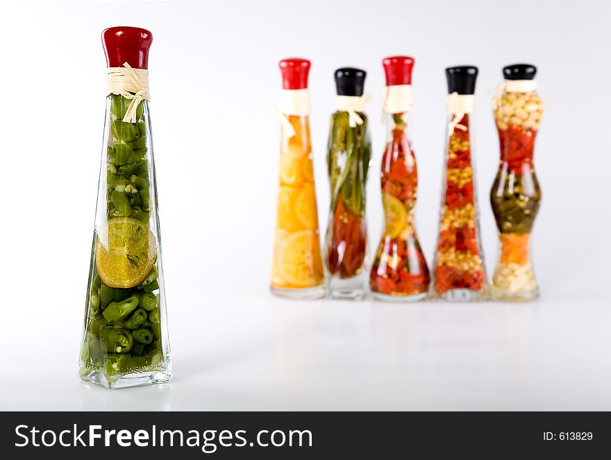 Decorative glass bottles filled with colorful fruits, vegetables and vinegar. Front bottle is in focus. Decorative glass bottles filled with colorful fruits, vegetables and vinegar. Front bottle is in focus.