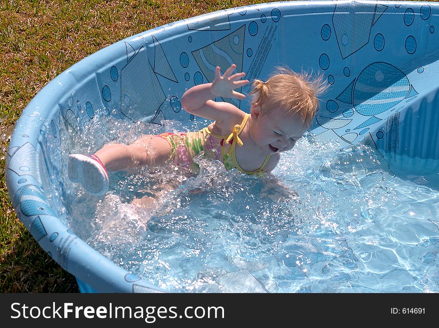 A small child is enjoying a backyard swimming pool. A small child is enjoying a backyard swimming pool