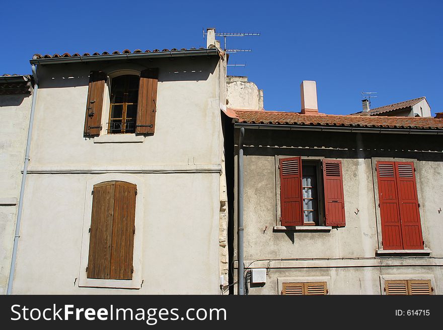 A building in the town of arles, france, with shutters on the windows. A building in the town of arles, france, with shutters on the windows