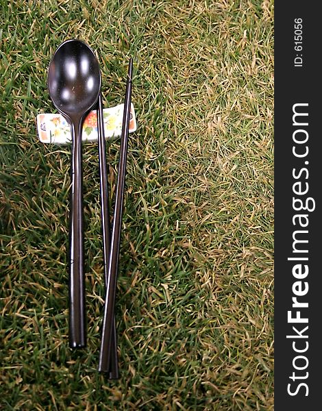 Spoon, chopsticks and chopstick rests on the grass. Spoon, chopsticks and chopstick rests on the grass