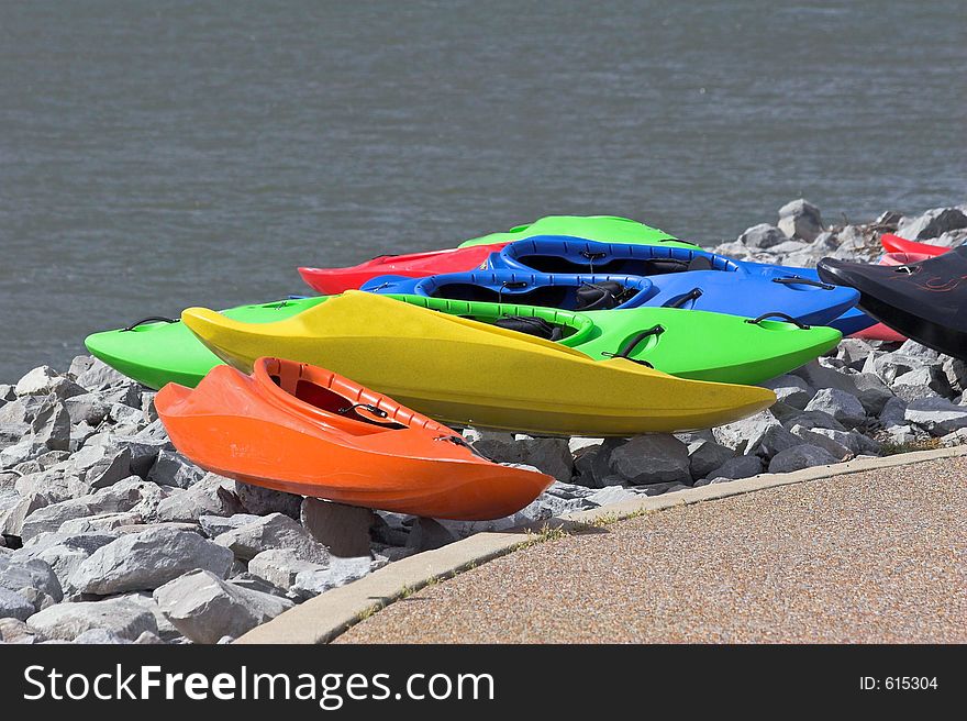 Line of colorful kayaks on bank waiting for use