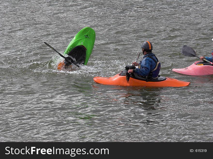 Kayaker practicing recovery from roll over with trainer watching. Kayaker practicing recovery from roll over with trainer watching