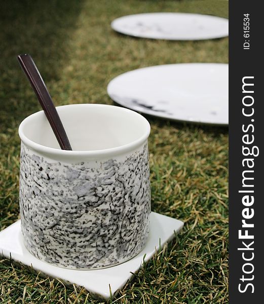 Pottery cup with spoon on the grass