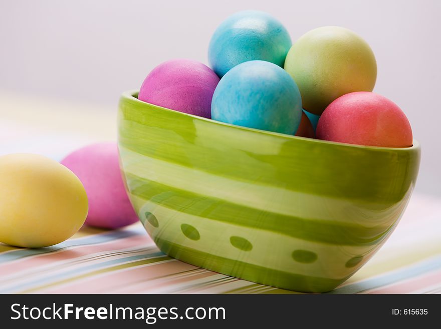 Bowl of Easter eggs in large green bowl sitting on stripped placemat. Bowl of Easter eggs in large green bowl sitting on stripped placemat.