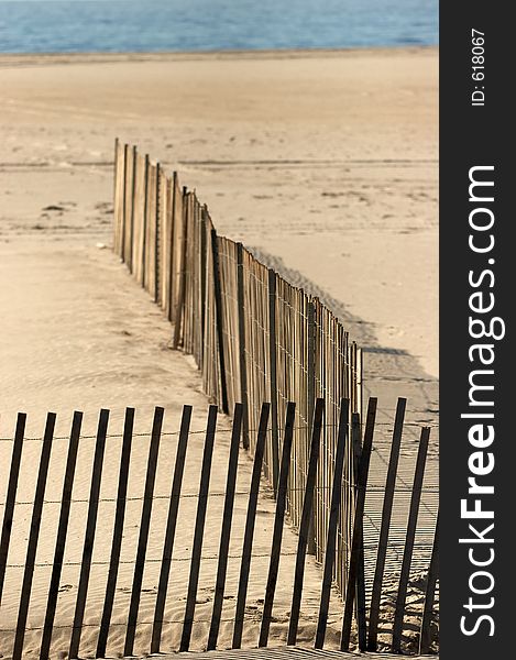 Ocean beach with a wood picket fence. Small portion of the fence is in focus. Ocean beach with a wood picket fence. Small portion of the fence is in focus.