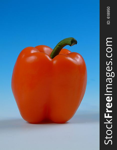 Studio image of a red pepper on a graduated blue background