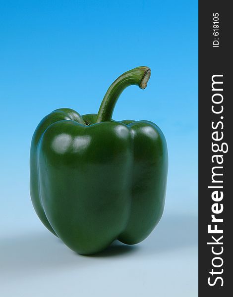 A studio image of a green pepper photographed on a graduated blue background