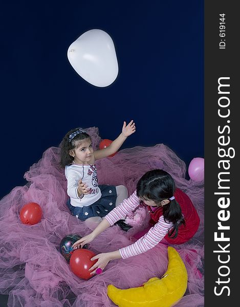 Two little girls playing with balloons in a fairy setup. Two little girls playing with balloons in a fairy setup