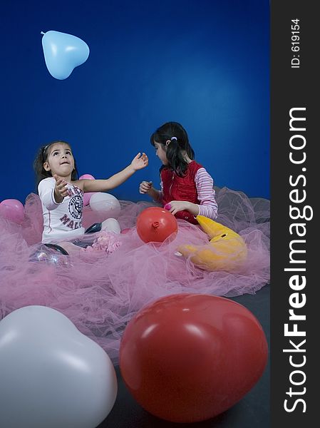Little girls playing with balloons surrounded by a pink veil. Little girls playing with balloons surrounded by a pink veil