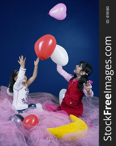 Young and beautiful girls playing with white and pink balloons. Young and beautiful girls playing with white and pink balloons