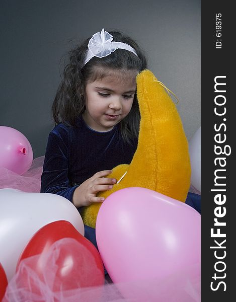 Sweet young girl playing with her plush moon surrounded by coloured balloons