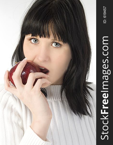 Beautiful young woman in white sweater eating red apple. Shot in studio over white. Beautiful young woman in white sweater eating red apple. Shot in studio over white.