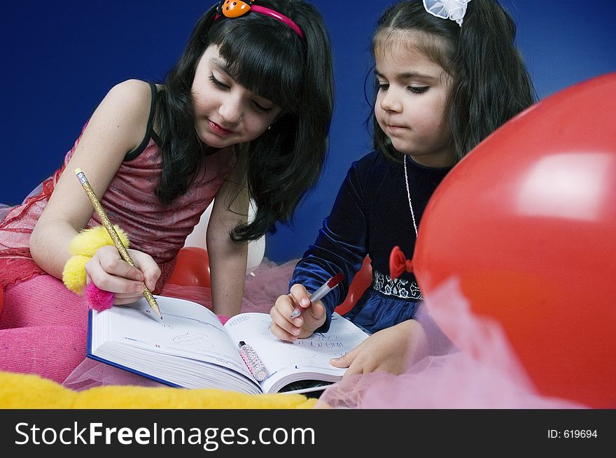 Two little girls focused upon writing in an agenda