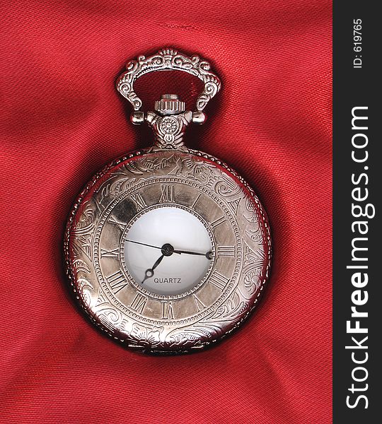 Silver pocket watch on red silk background