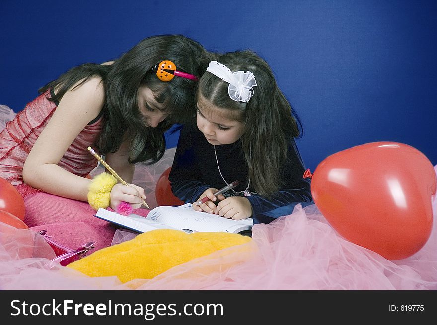 Two little girls writing in a big agenda. Two little girls writing in a big agenda