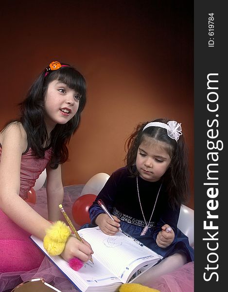 Two little girls writing in an agenda explaining to an auditorium. Two little girls writing in an agenda explaining to an auditorium