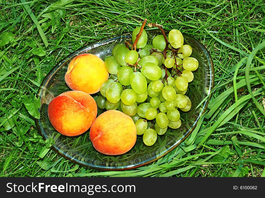 Fresh ripe peaches and grapes in green grass. Fresh ripe peaches and grapes in green grass