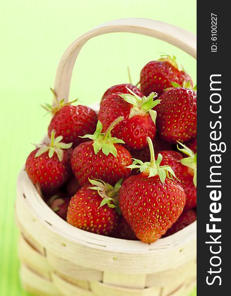 Wooden basket filled with strawberries over green background. Wooden basket filled with strawberries over green background