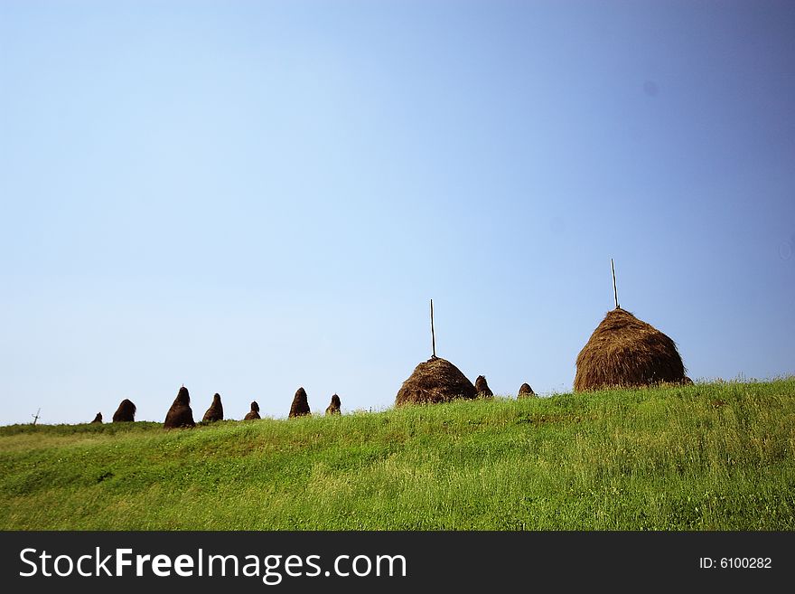 Haystacks on a background of the blue sky and green grass