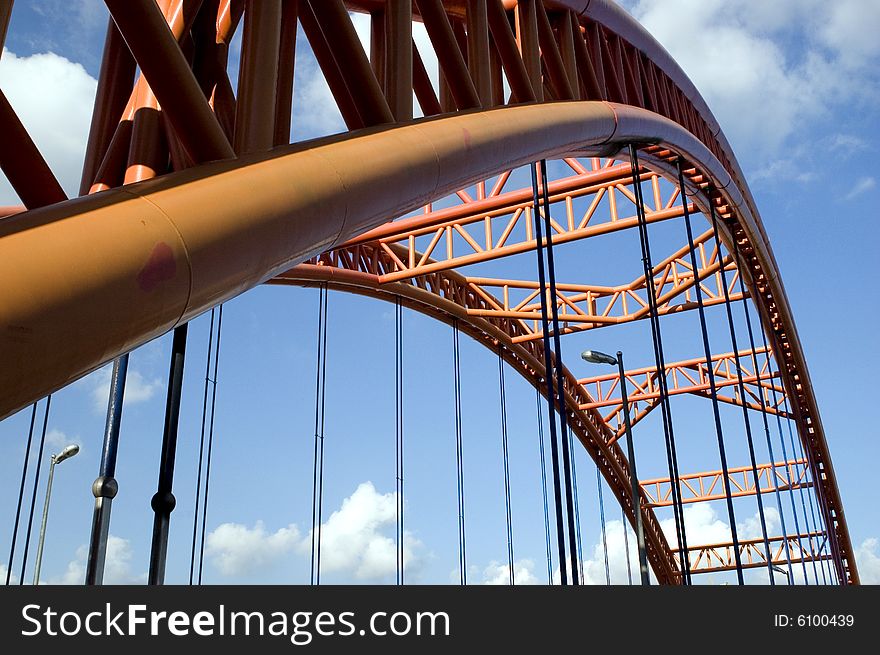 Original orange bridge structure with blue sky and clouds as bacground.